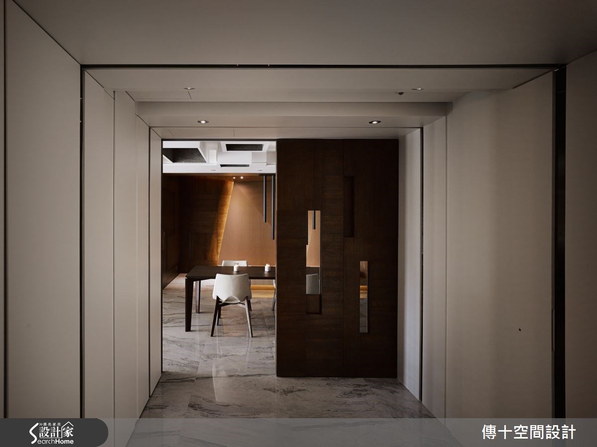 玄關在牆面加入隱藏鞋櫃空間,同時做出蜿蜒至天花板的垂直線條,營造引人入勝的漸進軸線感,盡頭處為深咖啡色木皮門片,採不規則狀鏤空設計,營造借景入室、若隱若現的視覺趣味。 玄關在牆面加入隱藏鞋櫃空間,同時做出蜿蜒至天花板的垂直線條,營造引人入勝的漸進軸線感,盡頭處為深咖啡色木皮門片,採不規則狀鏤空設計,營造借景入室、若隱若現的視覺趣味。